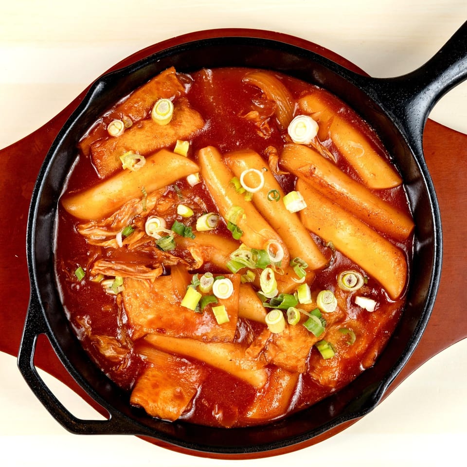 Mandurang's Tteokbokki, a Korean dish with rice cakes and fish cakes in red chili sauce, topped with scallions.