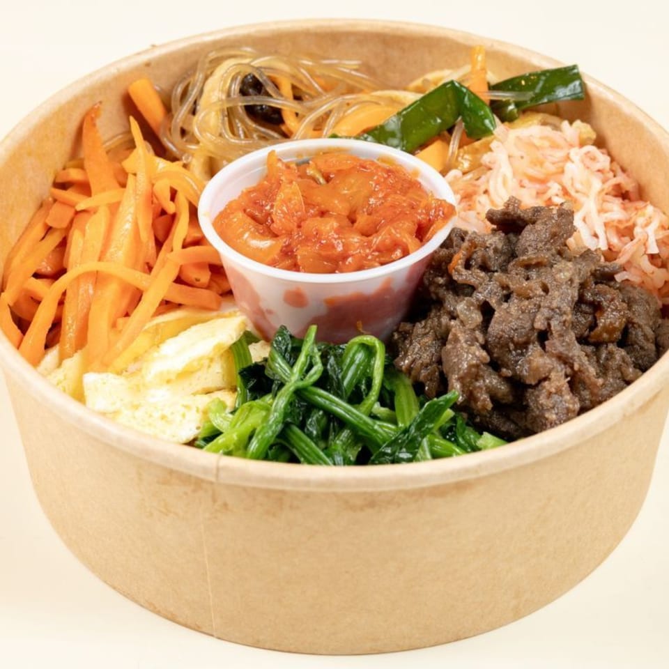 A Mandurang Korean bibimbap bowl with beef, kimchi, glass noodles, carrots, spinach, and egg.